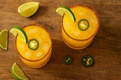 Mango chili margarita on the rocks with Tajín rim and lime slice.